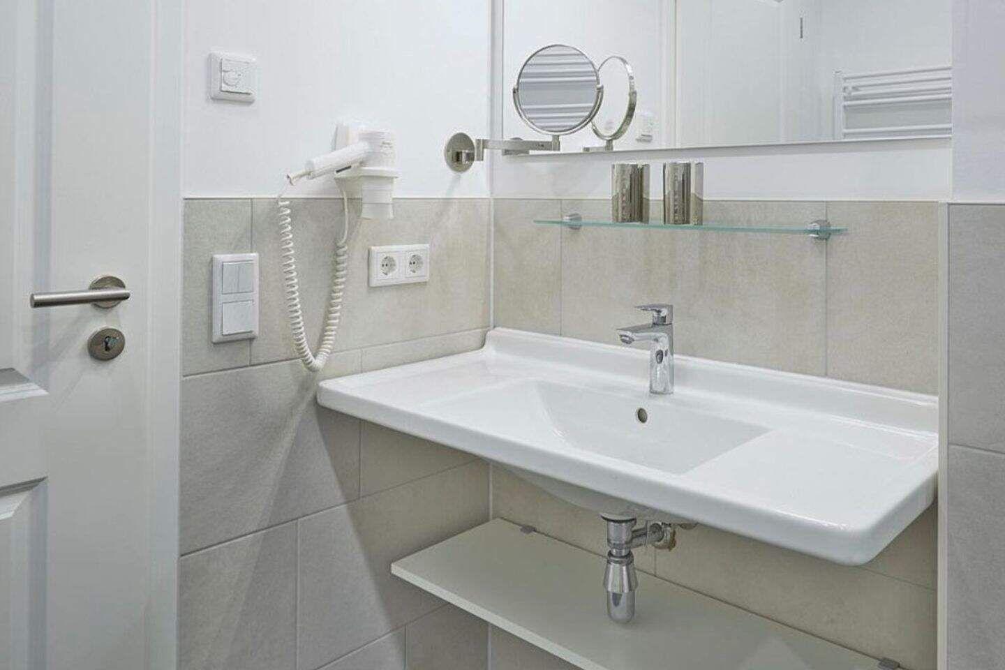 Badezimmer mit Waschbecken, Spiegel und Handtuchhalter.