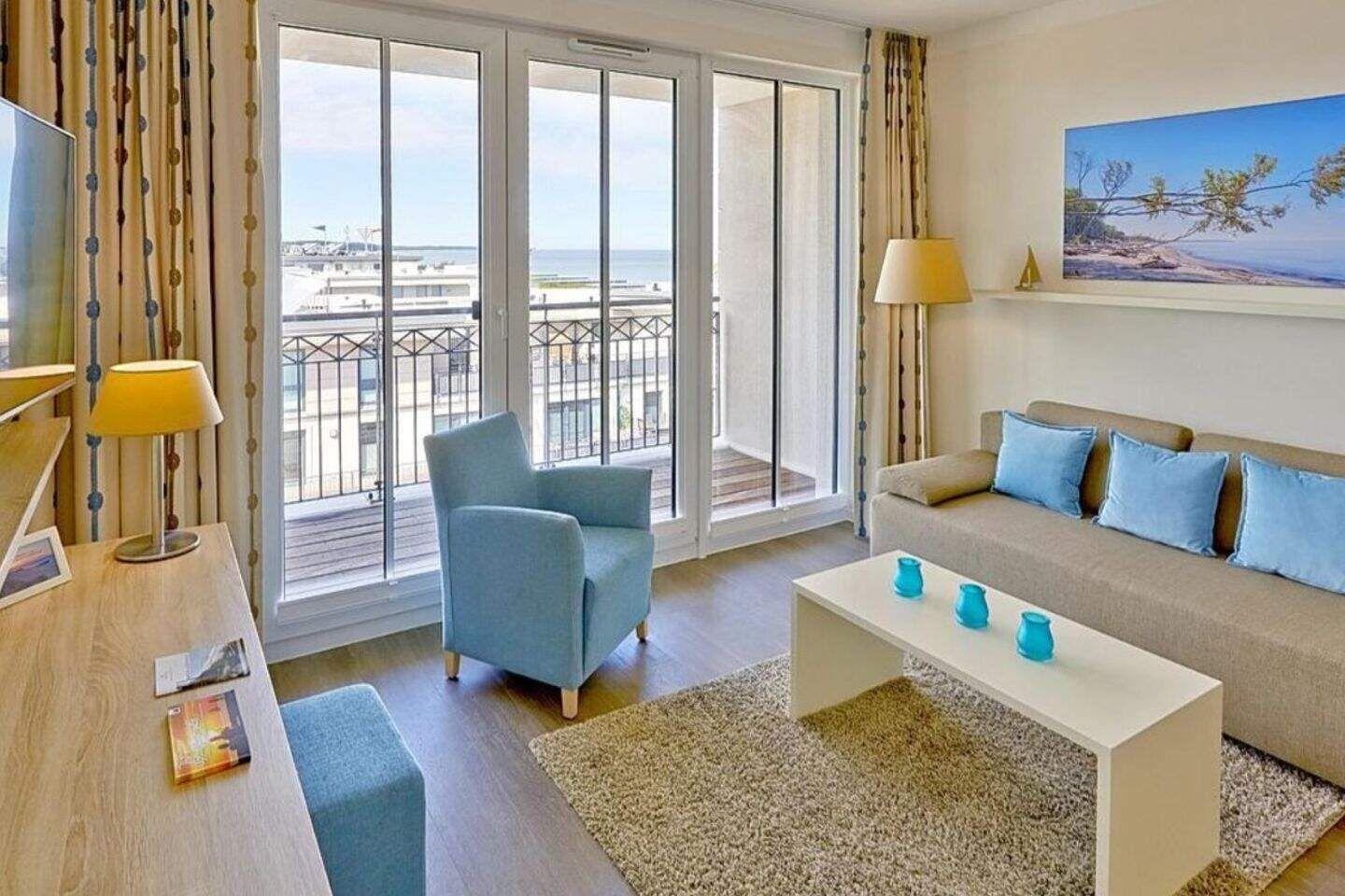 Wohnzimmer mit Sofa, Sessel und Balkon mit Meerblick.