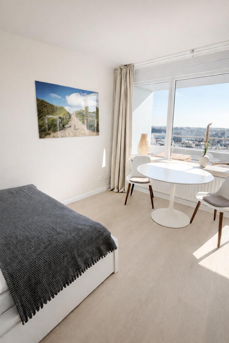 Zimmer mit Bett, Esstisch und Blick auf die Stadt.