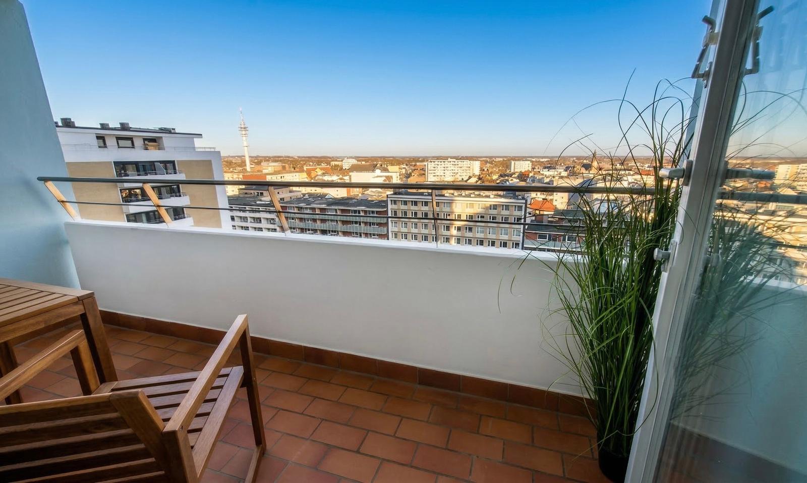 Terrasse mit Holzmöbeln und Blick auf die Stadt