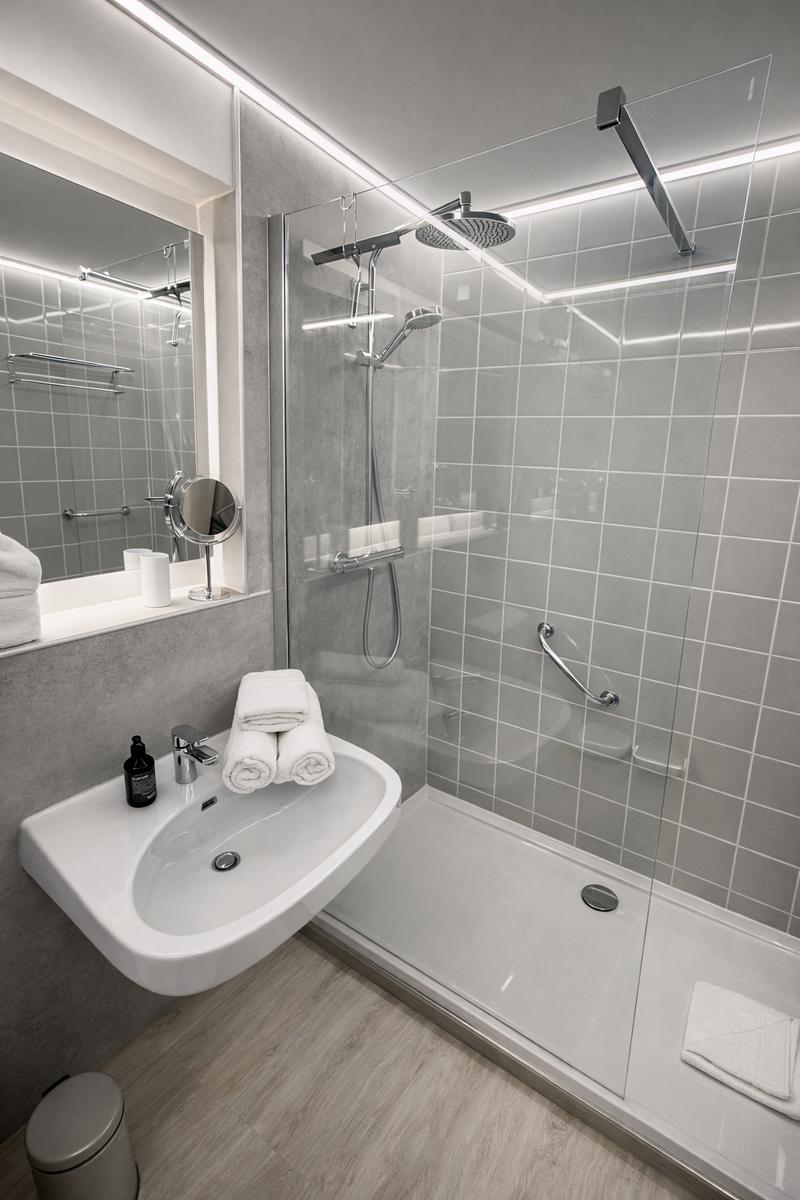 Moderne Dusche mit Duschbrause und Handbrause. Waschbecken mit Spiegel und Handtücher.