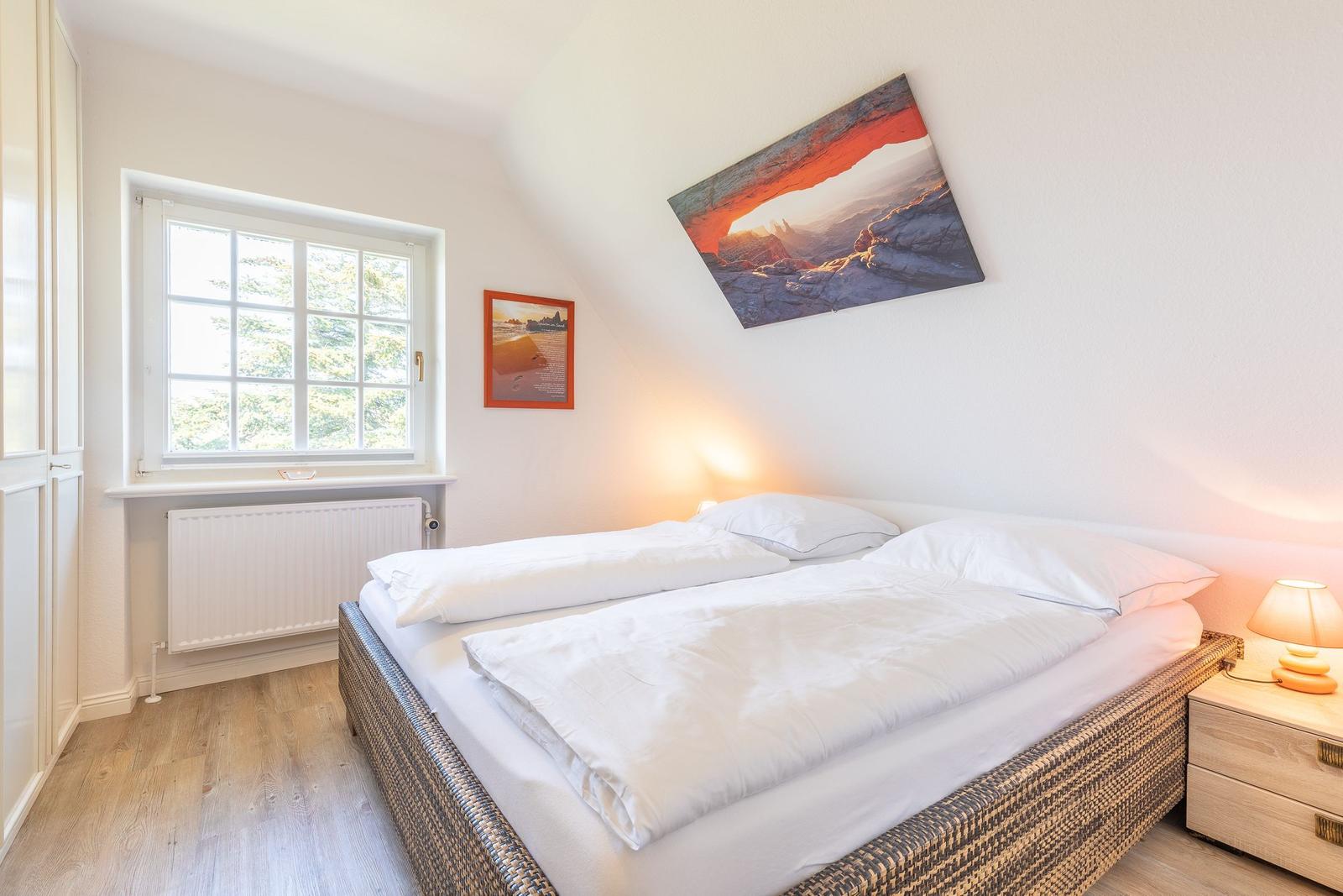 Schlafzimmer mit Doppelbett, Fenster und Wandbild.