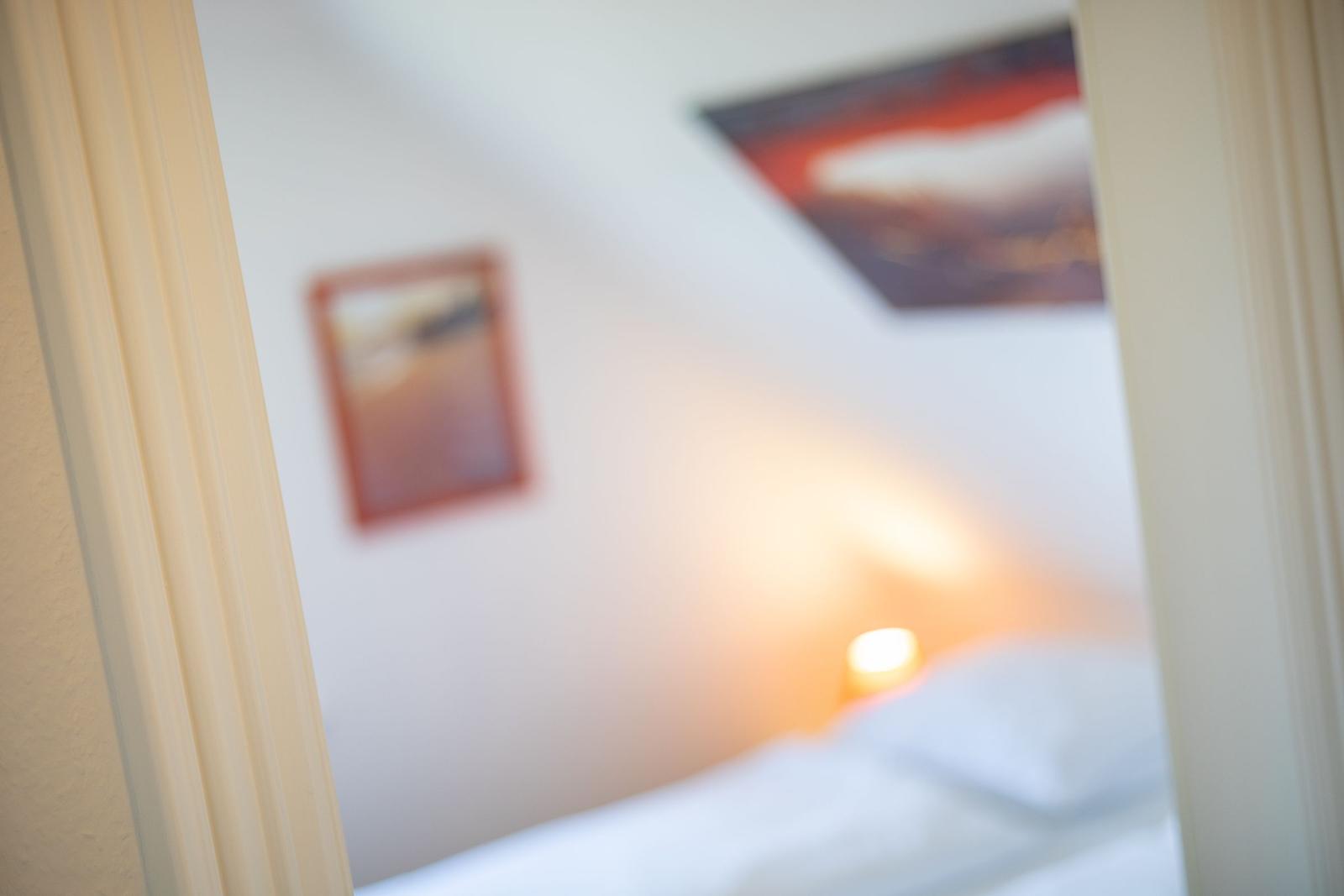 Schlafzimmer mit Bett, Wandbildern und warmem Licht.