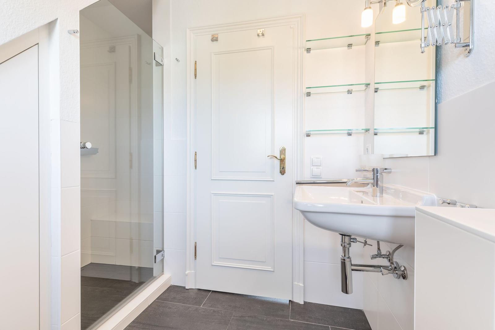 Badezimmer mit Dusche, Waschbecken und Spiegelschrank.