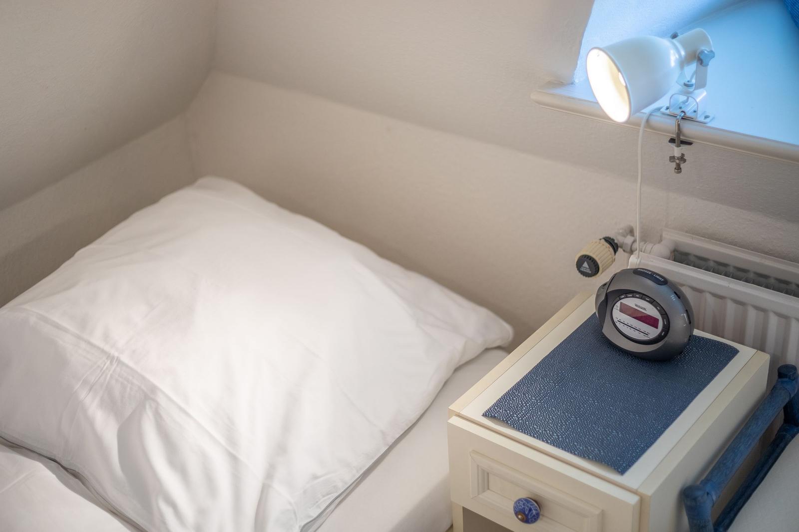 Schlafzimmer mit Bett, Nachttisch und Lampe an Fensterbank