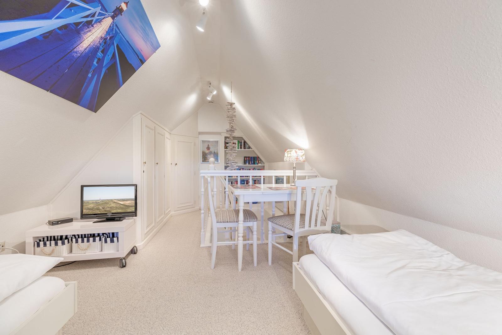 Schlafzimmer mit Doppelbett, Esstisch und Fernseher unter Dachschrägen.