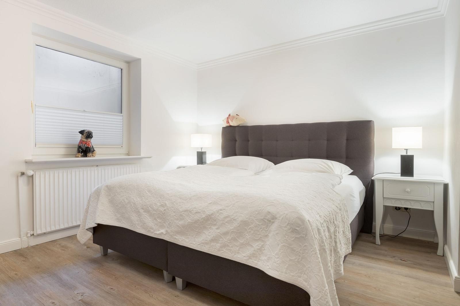 Schlafzimmer mit Bett, Nachttisch und Fenster mit Jungenfigur.