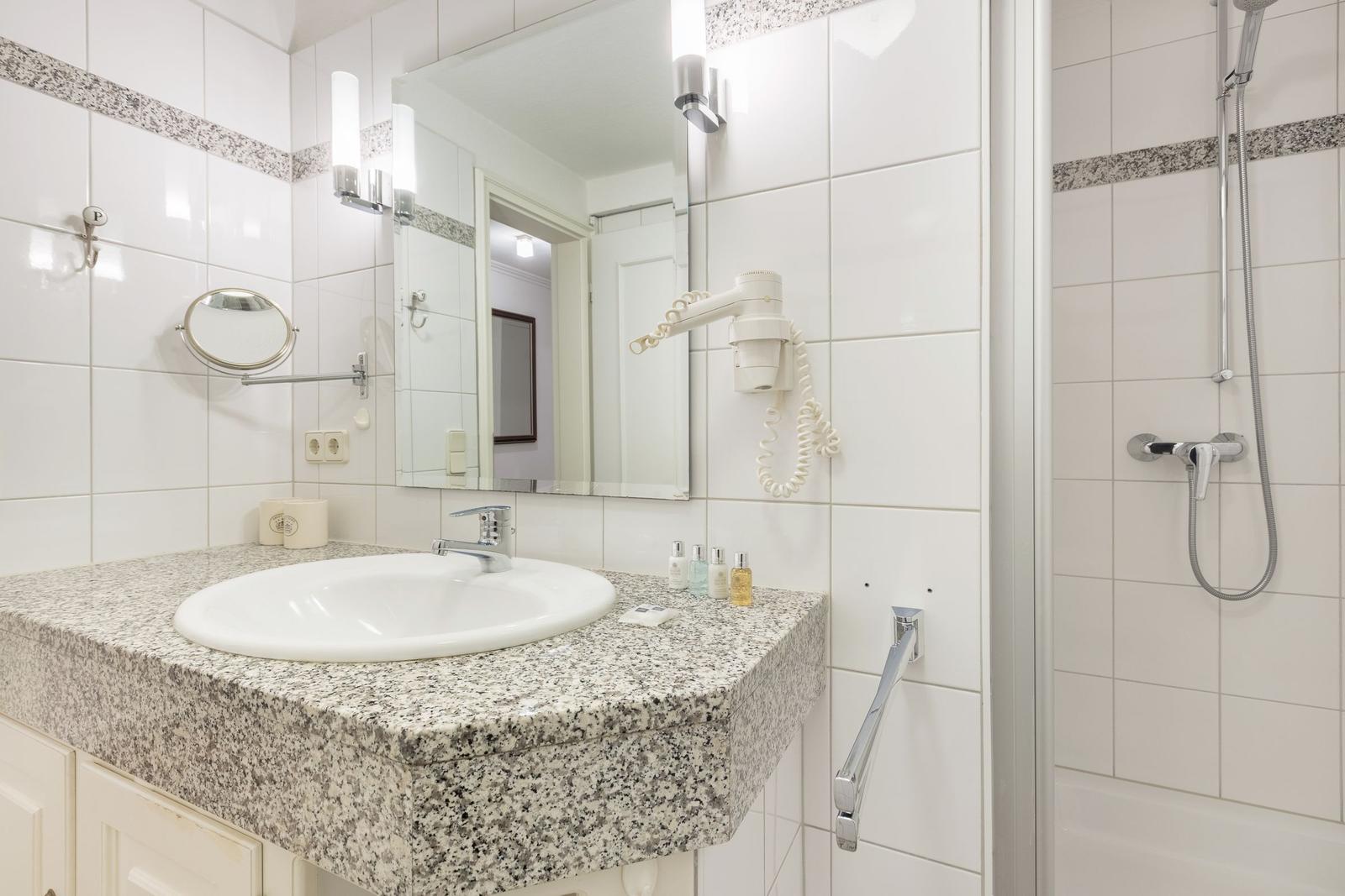 Badezimmer mit Waschbecken, Spiegel und Dusche