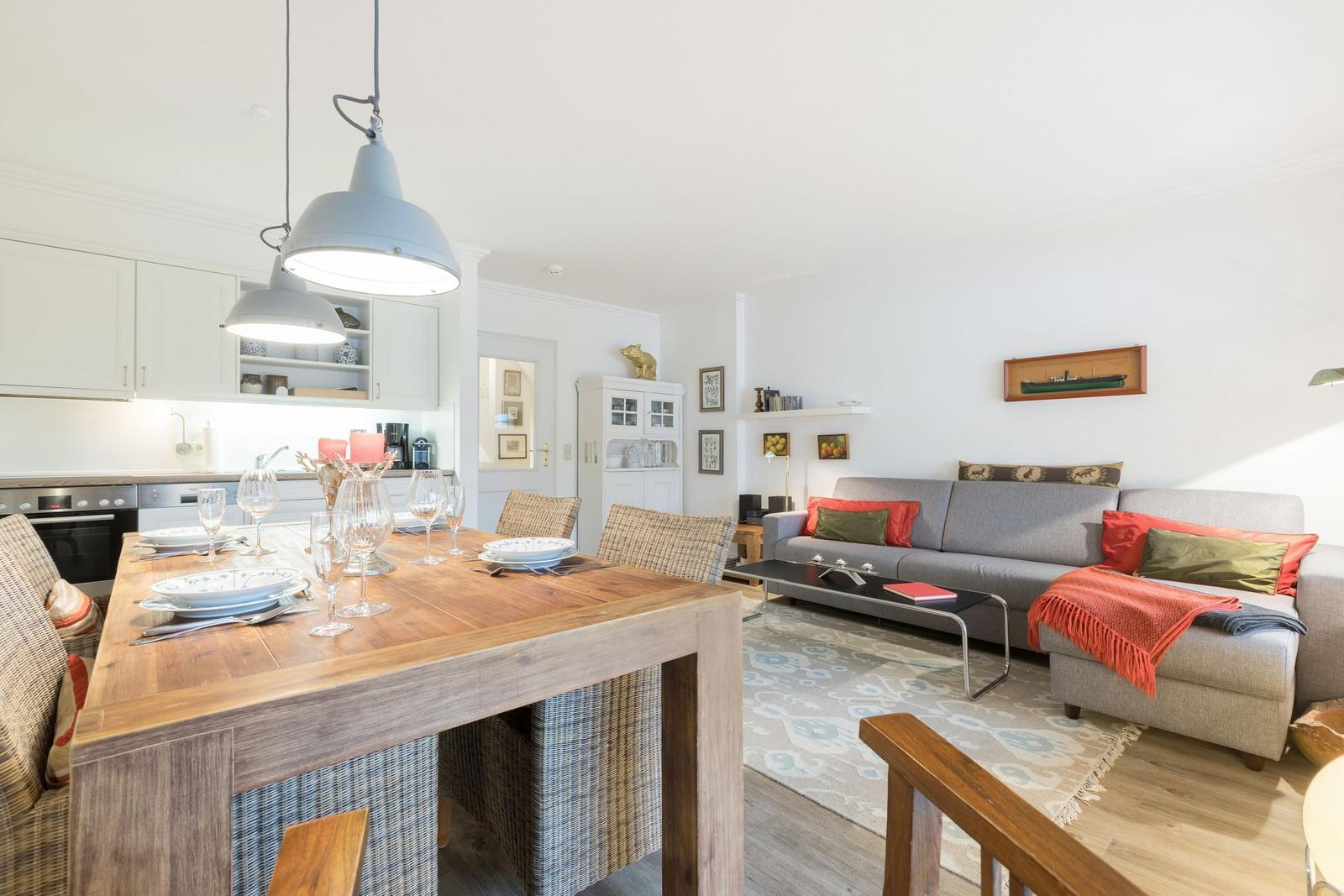 Essbereich mit Holztisch und Wohnzimmer mit Sofa und Couchtisch.