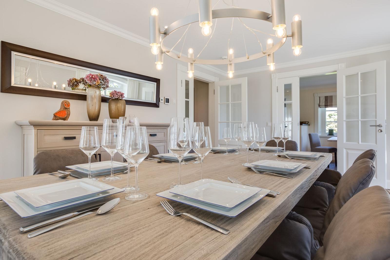 Esszimmer mit langem Holztisch, Stühlen und moderner Deckenleuchte.