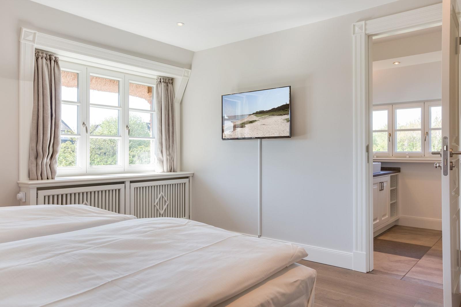 Schlafzimmer mit Doppelbett, TV und Blick auf grüne Landschaft.