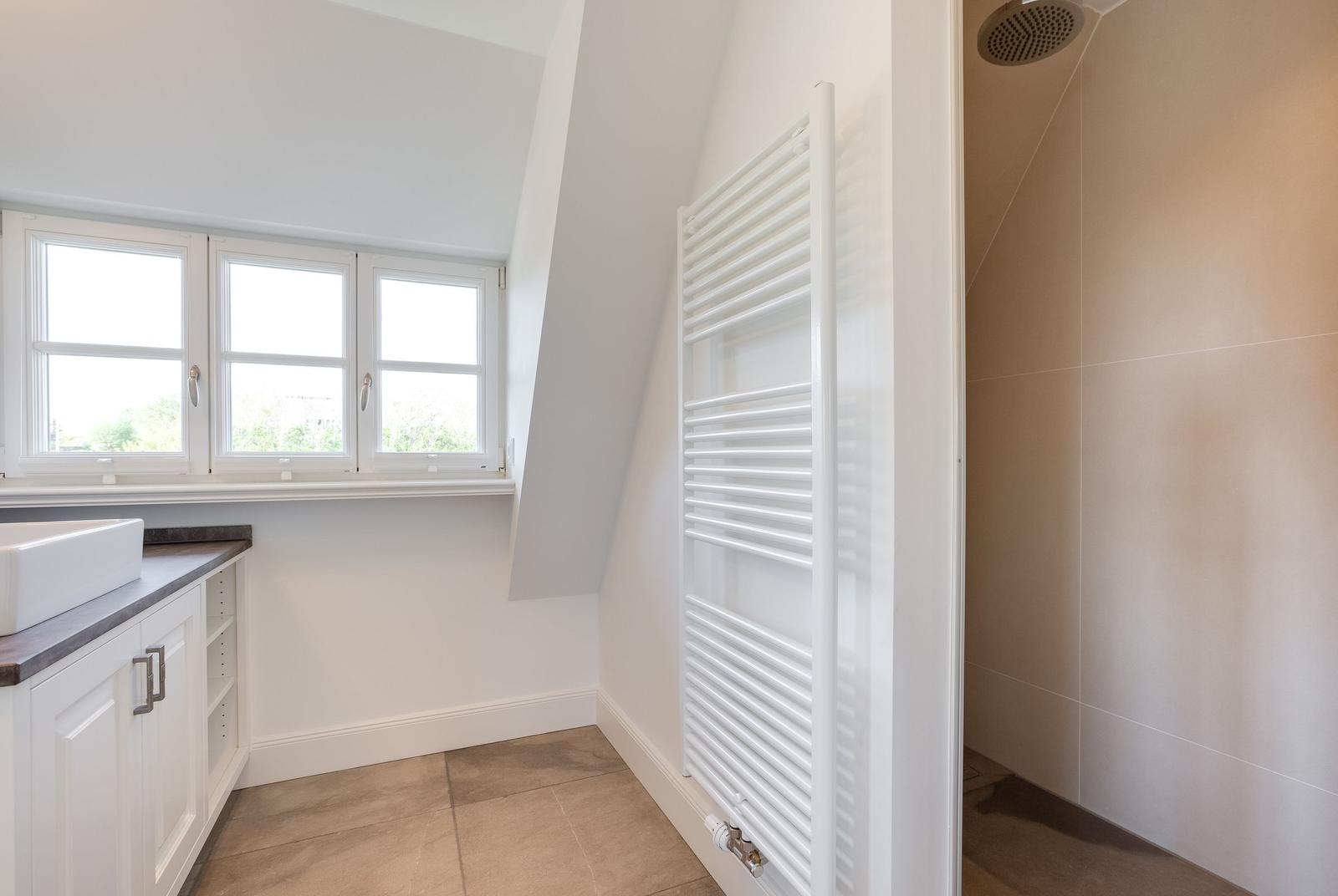 Badezimmer mit Dusche, Heizkörper und Fenster