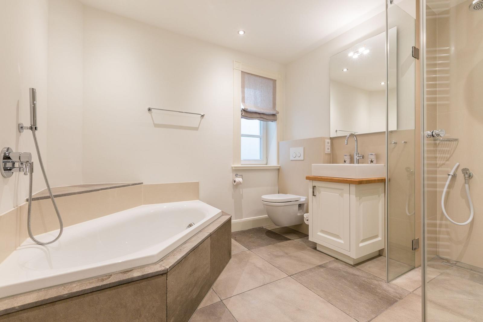 Badezimmer mit Badewanne, Dusche, Waschbecken und Toilette.