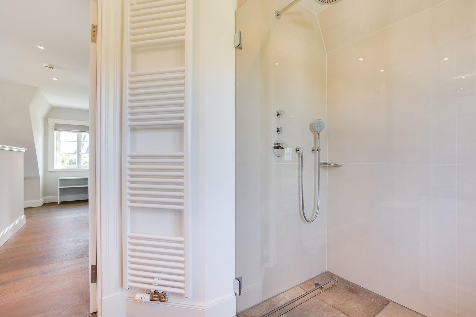 Dusche mit Duschbrause und Heizkörper an der Wand