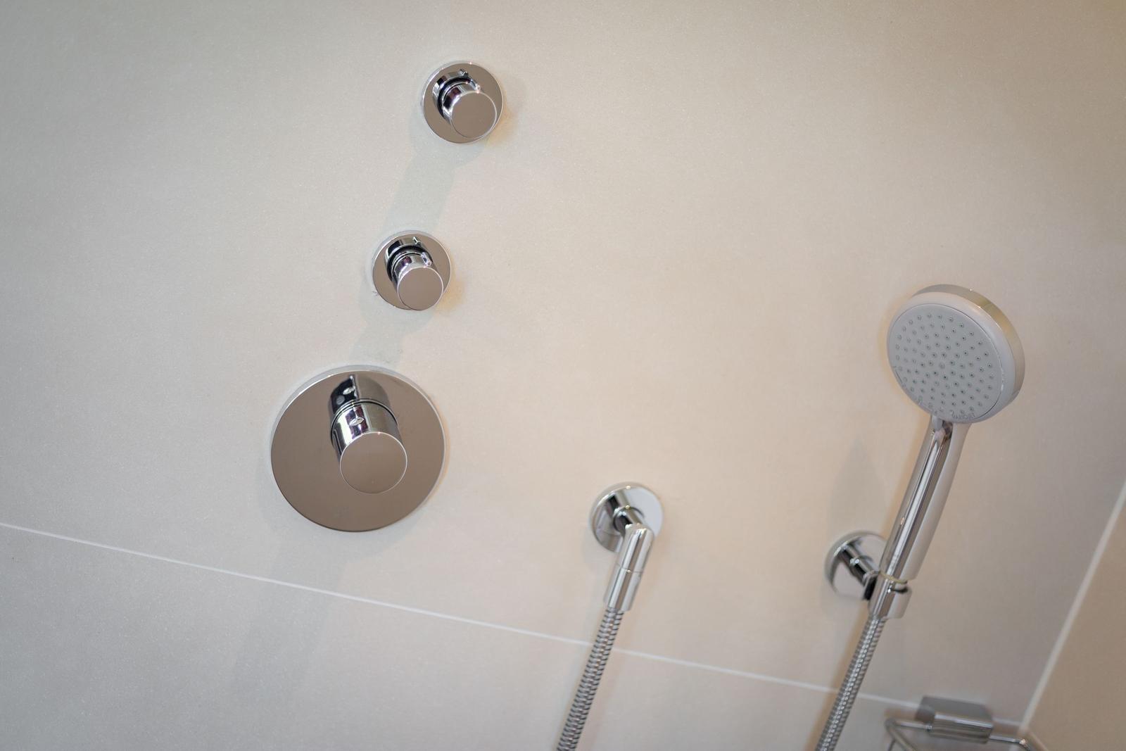 Duschkopf und Bedienelemente an der Wand