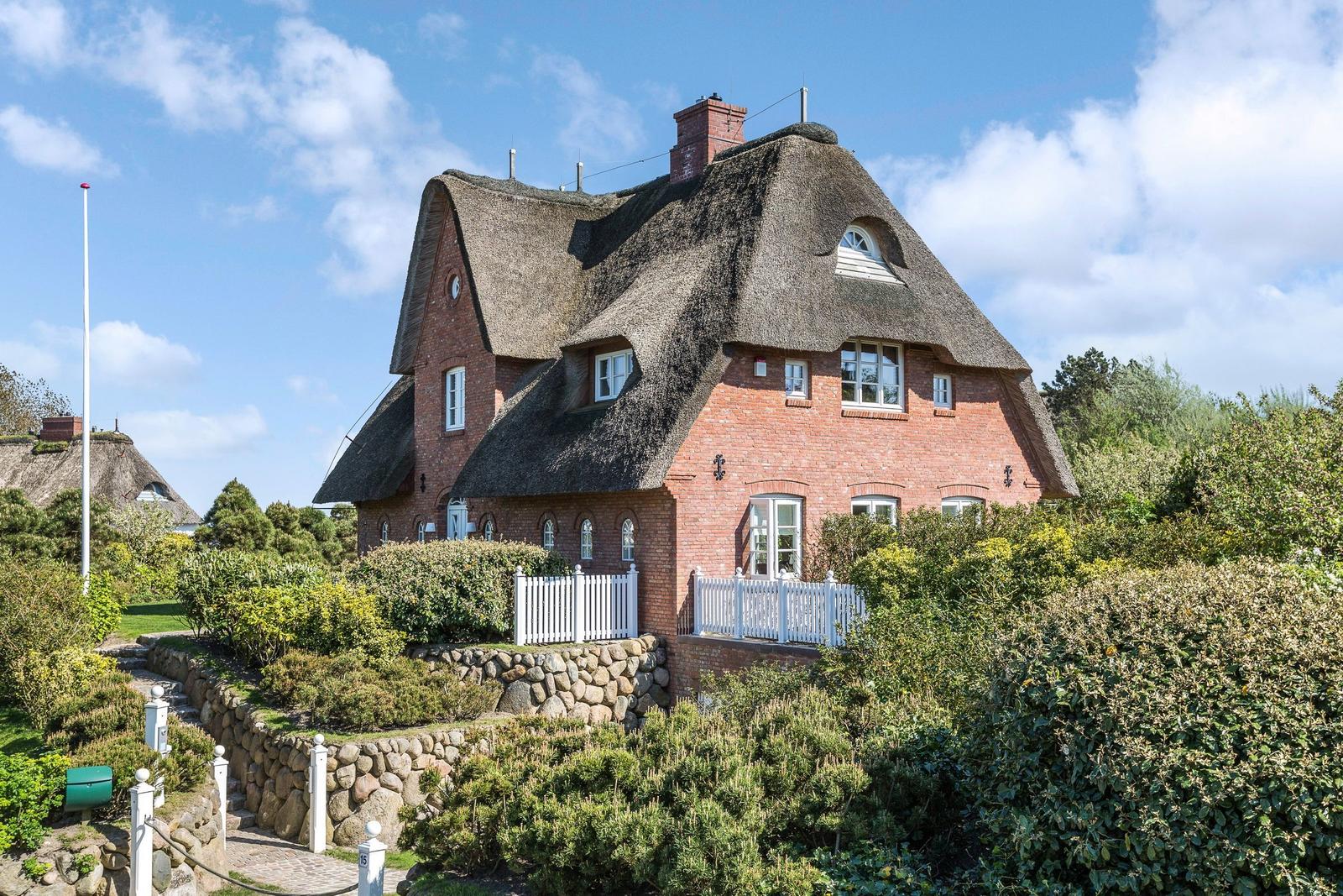 Rotes Backsteinhaus mit Strohdach und weißem Geländer