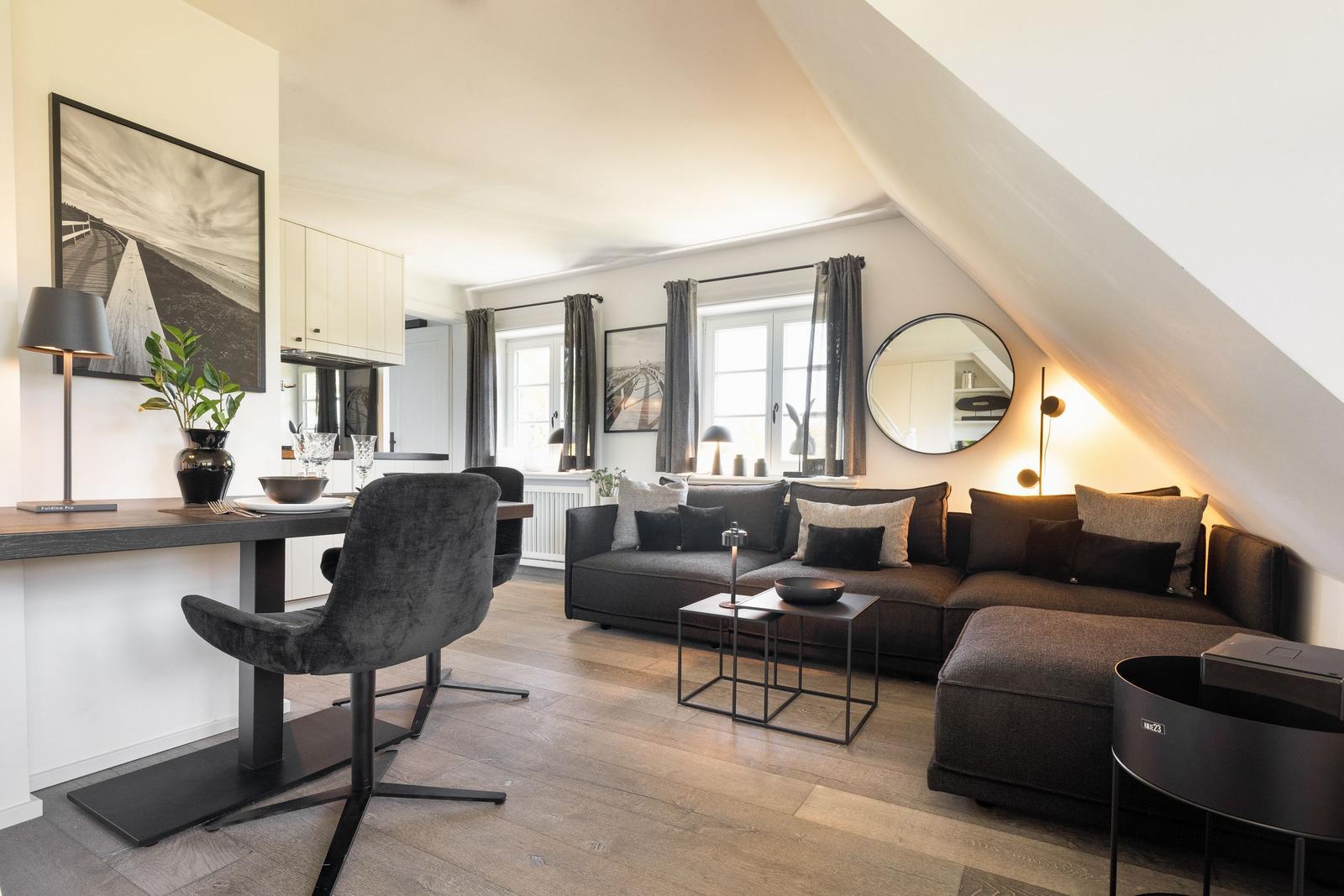 Wohnbereich mit Sofa, Esstisch und Schlafbereich unter Dachschräge.