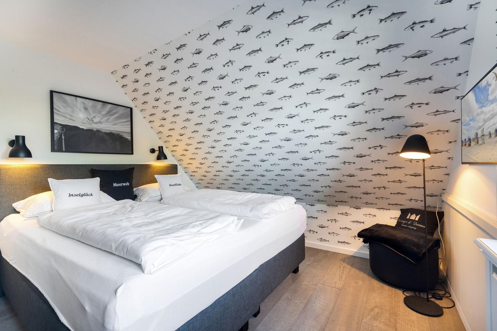 Schlafzimmer mit Bett, Fischmotivwand und Stehlampe.