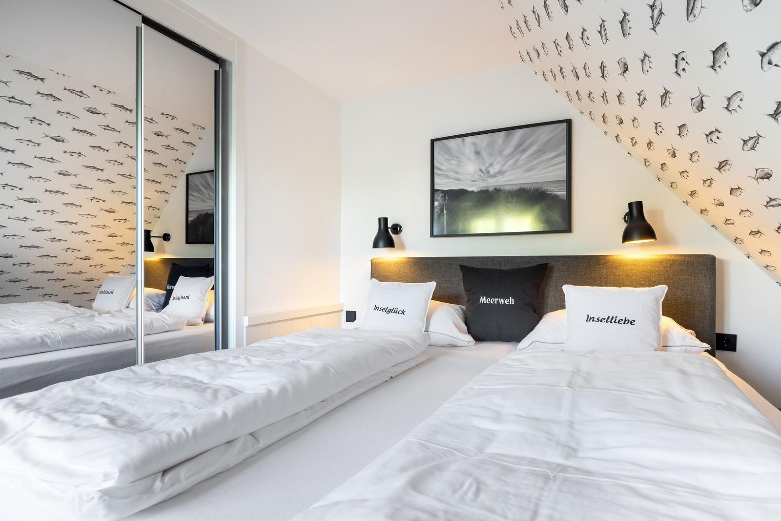 Zwei Betten unter schräger Decke mit Fisch壁纸 und Wandbild.