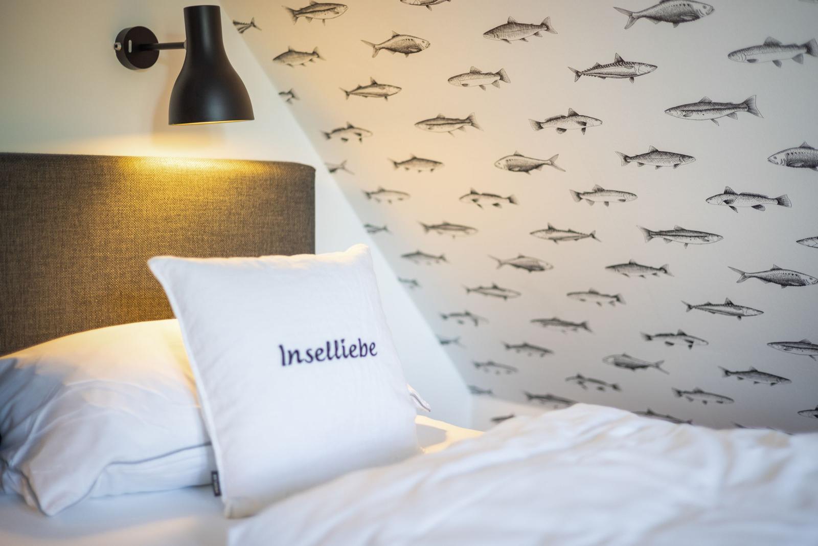 Schlafzimmer mit Fischmotiv-Wand und Kissen mit Aufdruck.