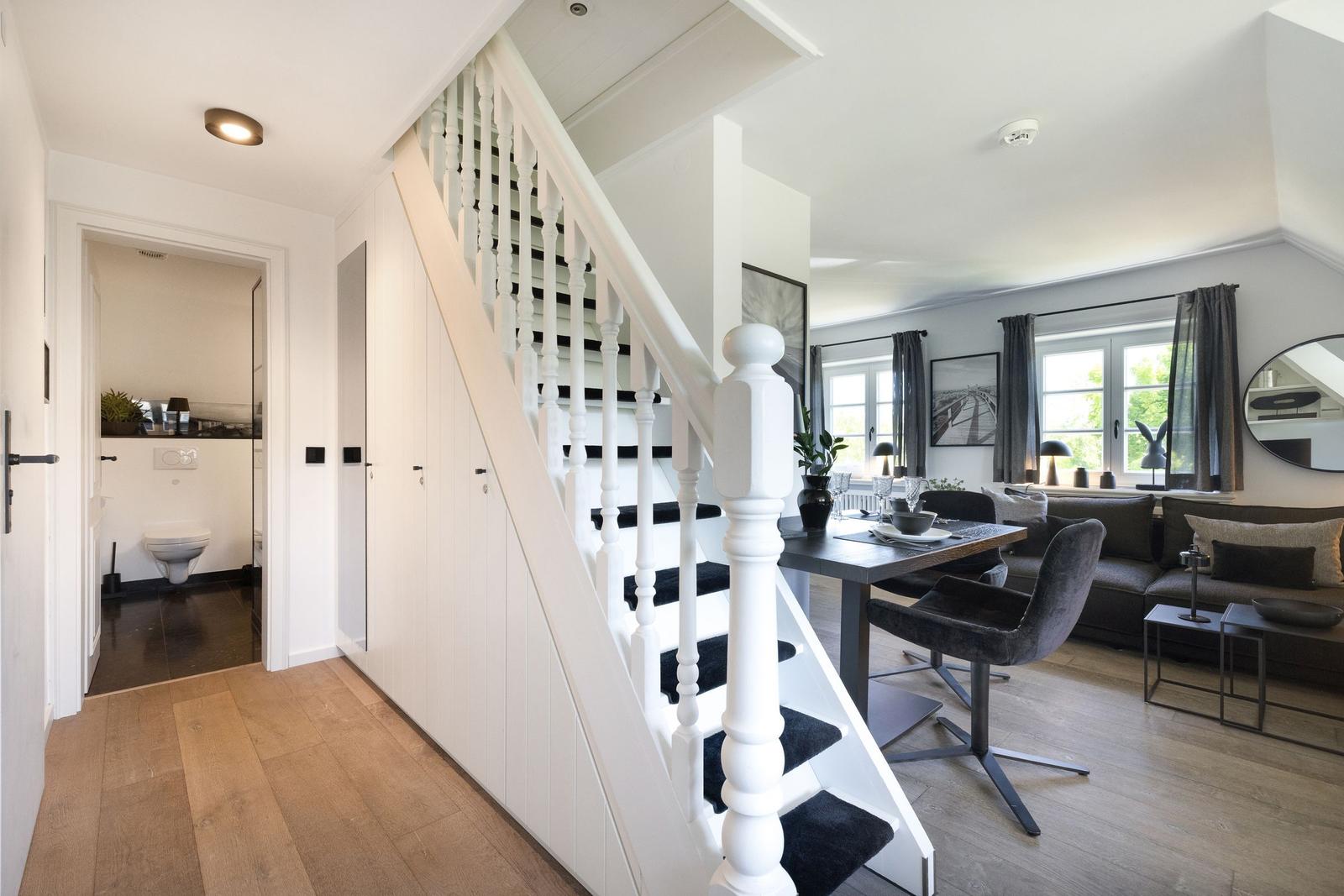 Haus mit Treppe, Essbereich und Wohnzimmer. Toilette im Hintergrund.