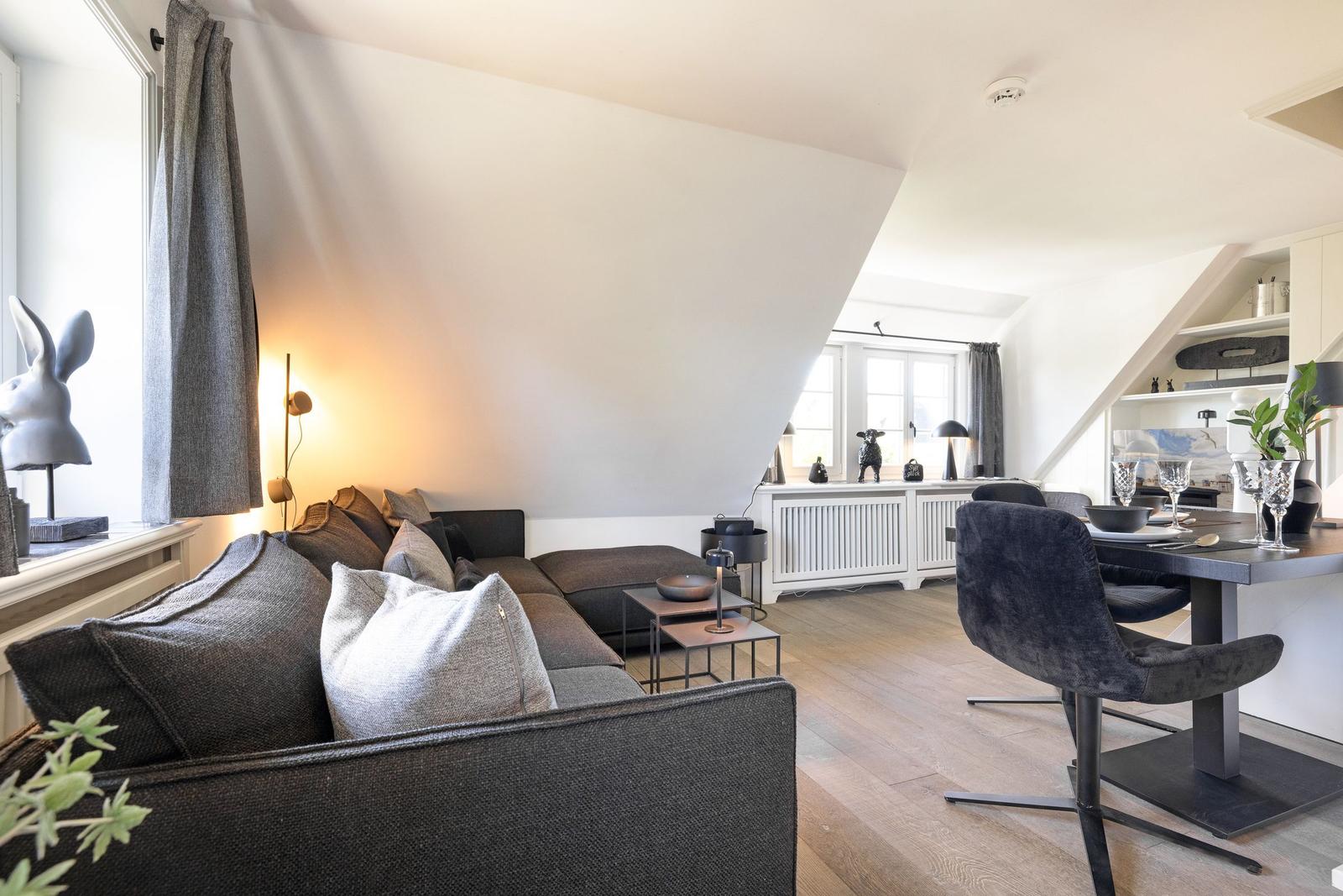 Wohn- und Essbereich mit Sofa, Tisch und Stühlen unter Dachschrägen.