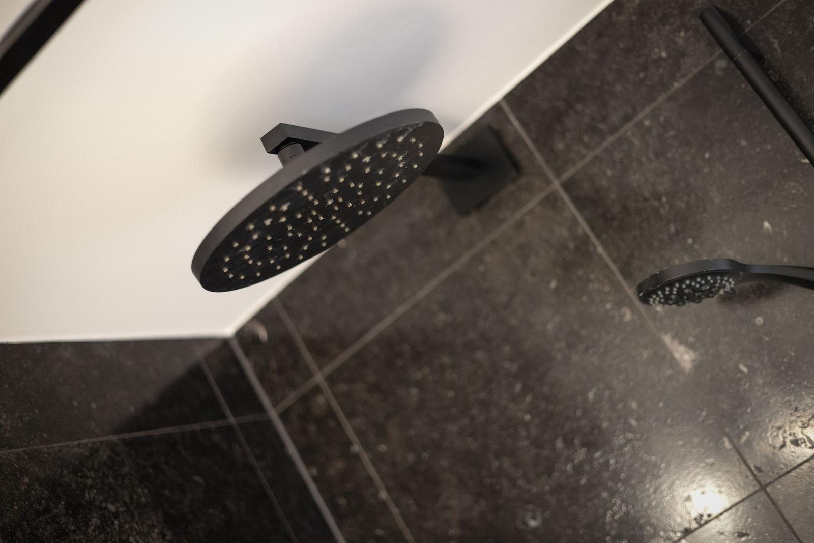 Duschkopf und Handbrause in schwarzem Design auf dunklem Boden