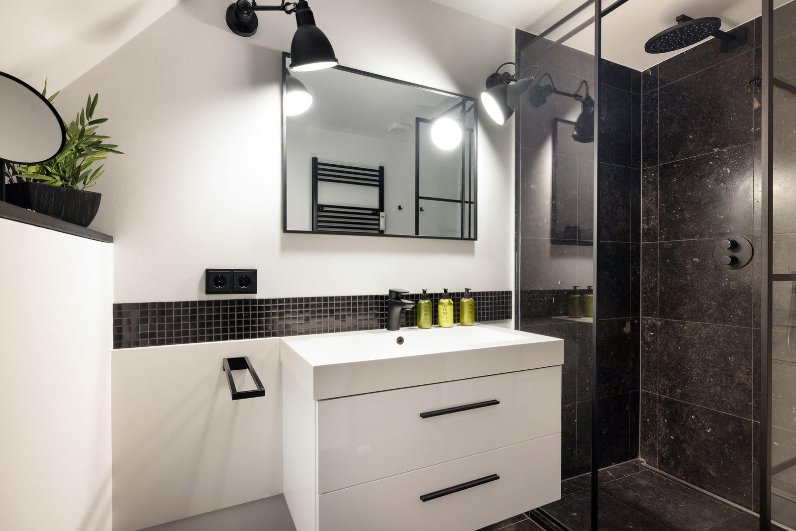 Badezimmer mit Dusche, Waschtisch und Spiegel
