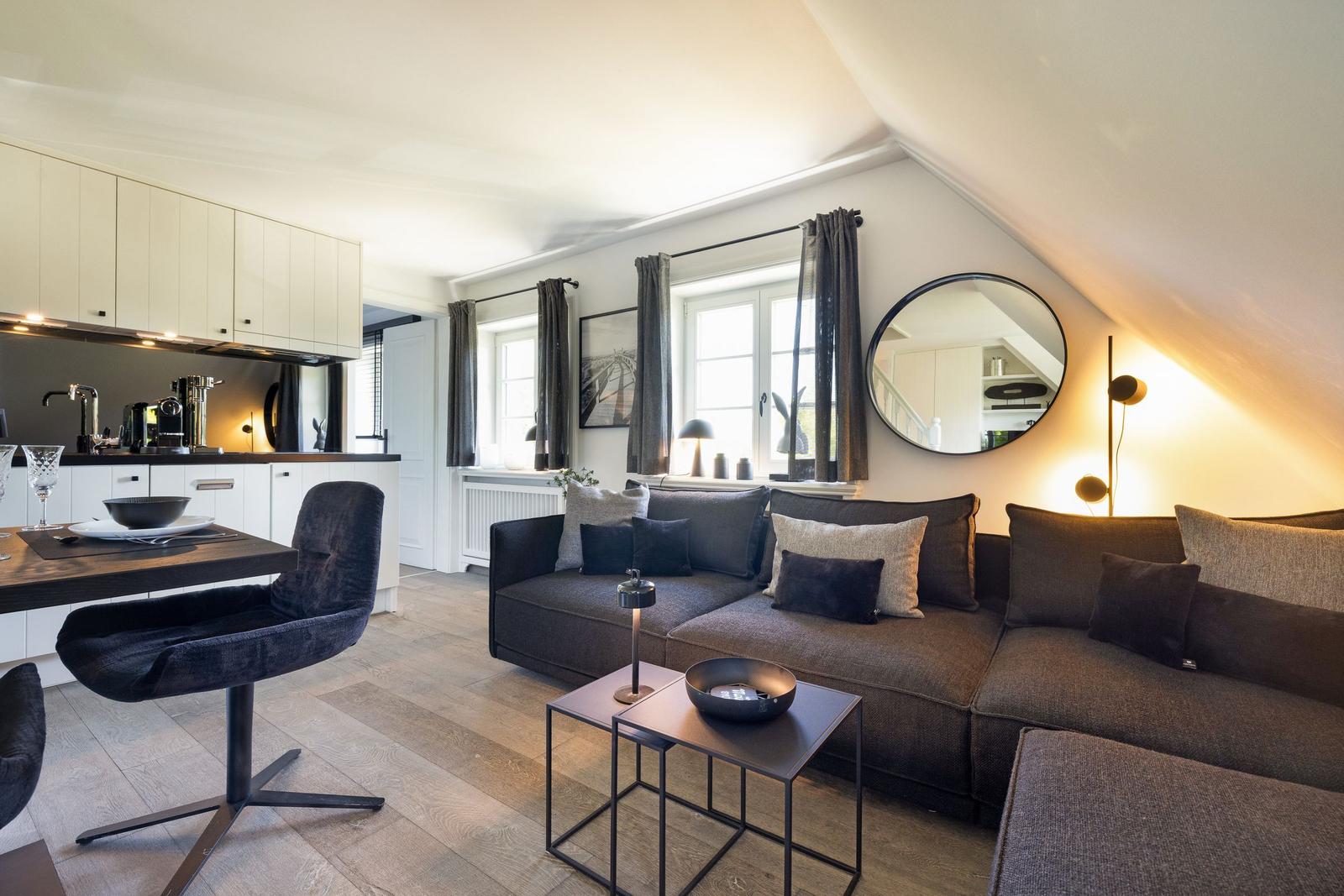 Wohnbereich mit Sofa, Tisch und Küchenzeile unter schrägem Dach