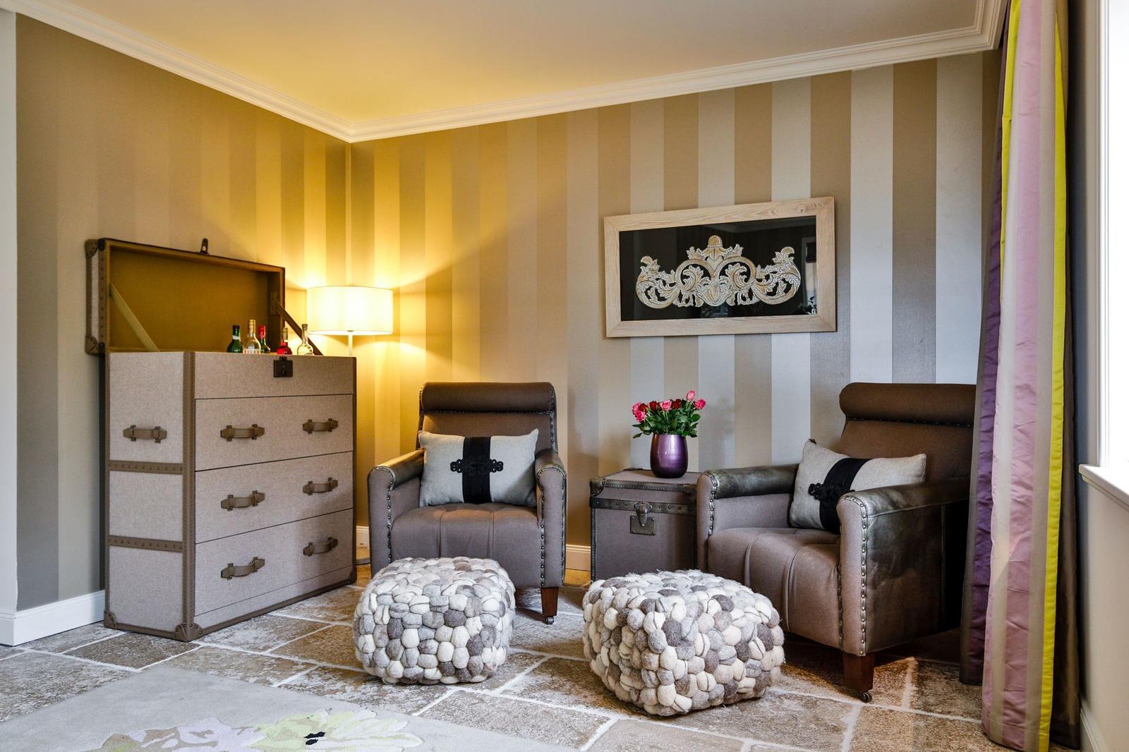Zwei Sessel mit Kissen, zwei Hocker, Schrank und Wandbild.