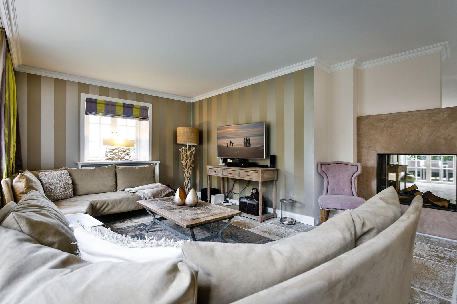 Wohnzimmer mit Sofa, Fernseher und Kamin
