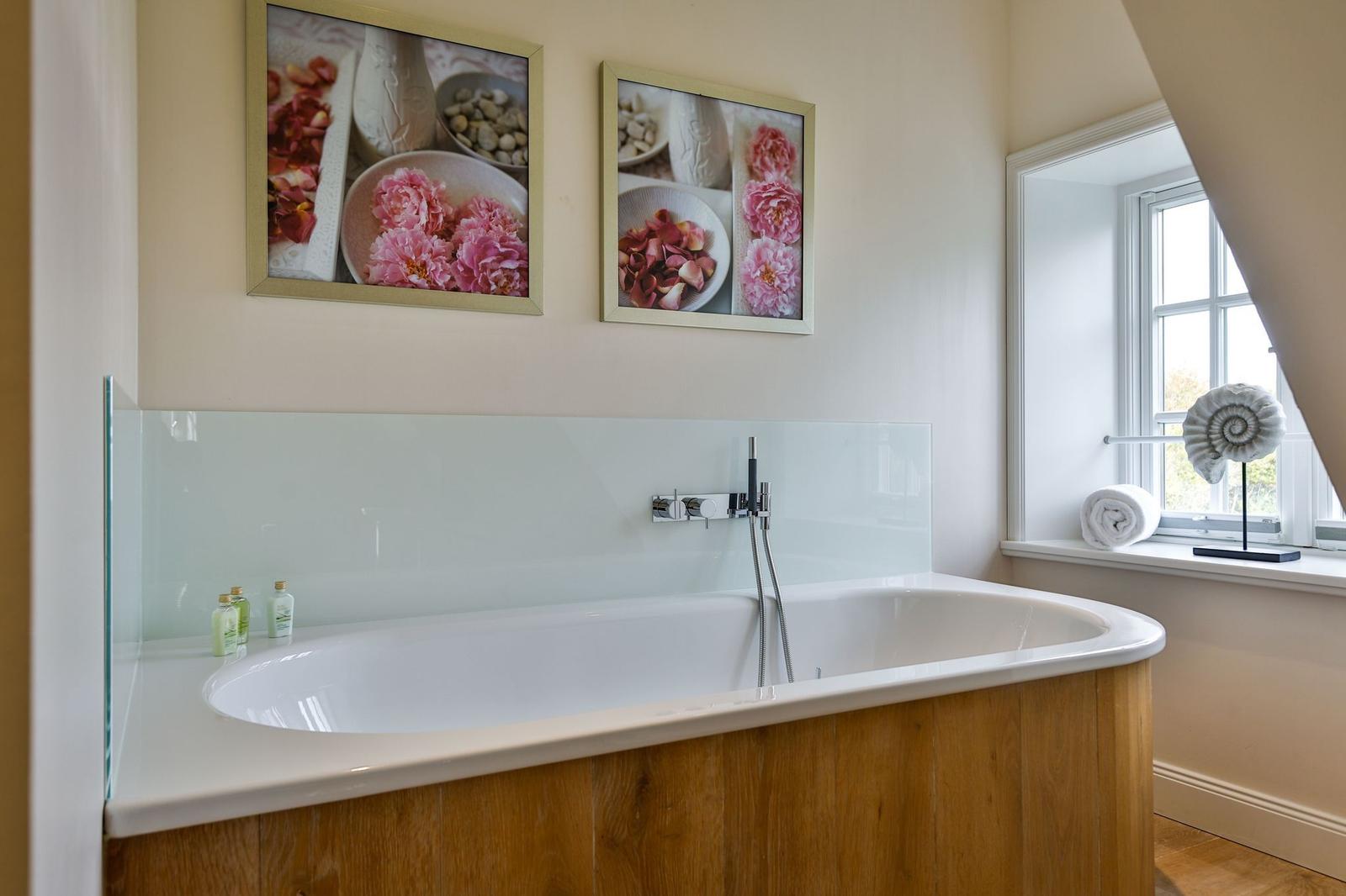 Bad mit Whirlpool, Wandbildern und Fenster mit Handtuch.