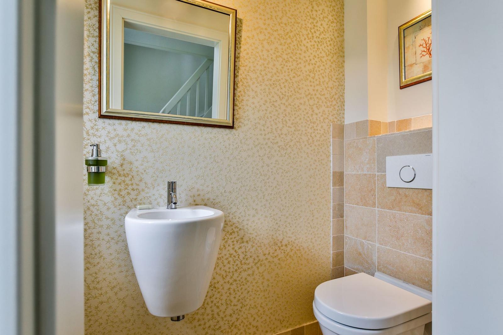Badezimmer mit Toilette, Waschbecken und Spiegel an der Wand.