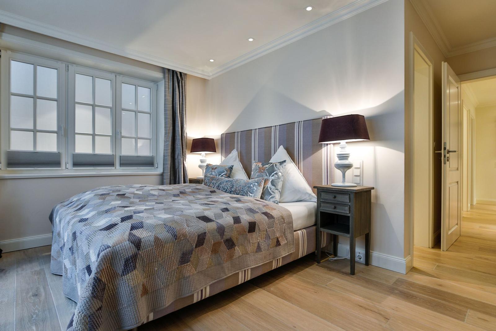 Schlafzimmer mit Bett, Nachttischen und Fenster.