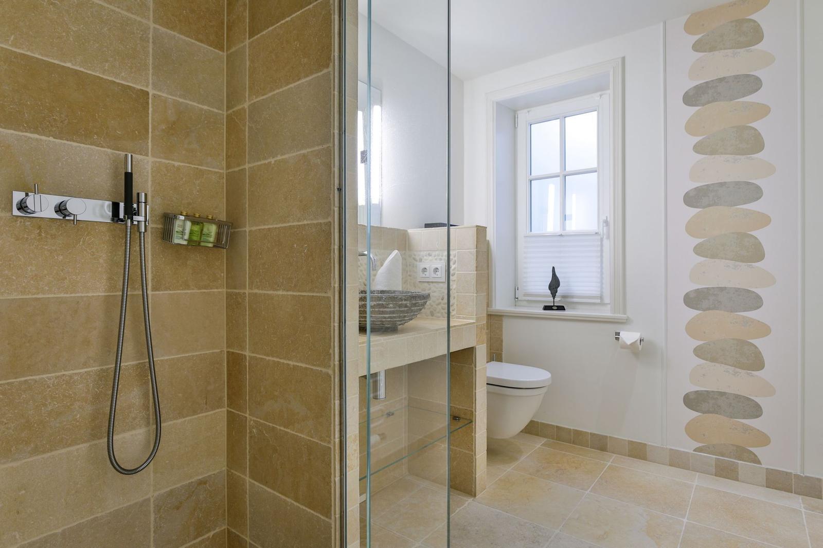 Dusche mit Glaswand, Waschbecken und Toilette in moderner Badezimmerausstattung.