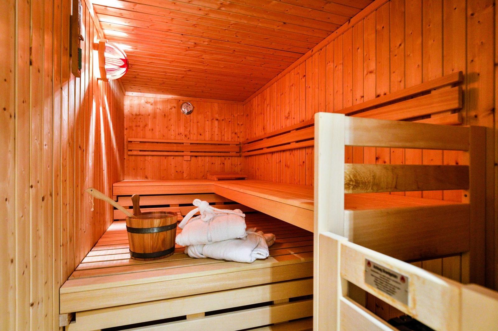 Sauna mit Holzbank, Bademantel und Eimer.