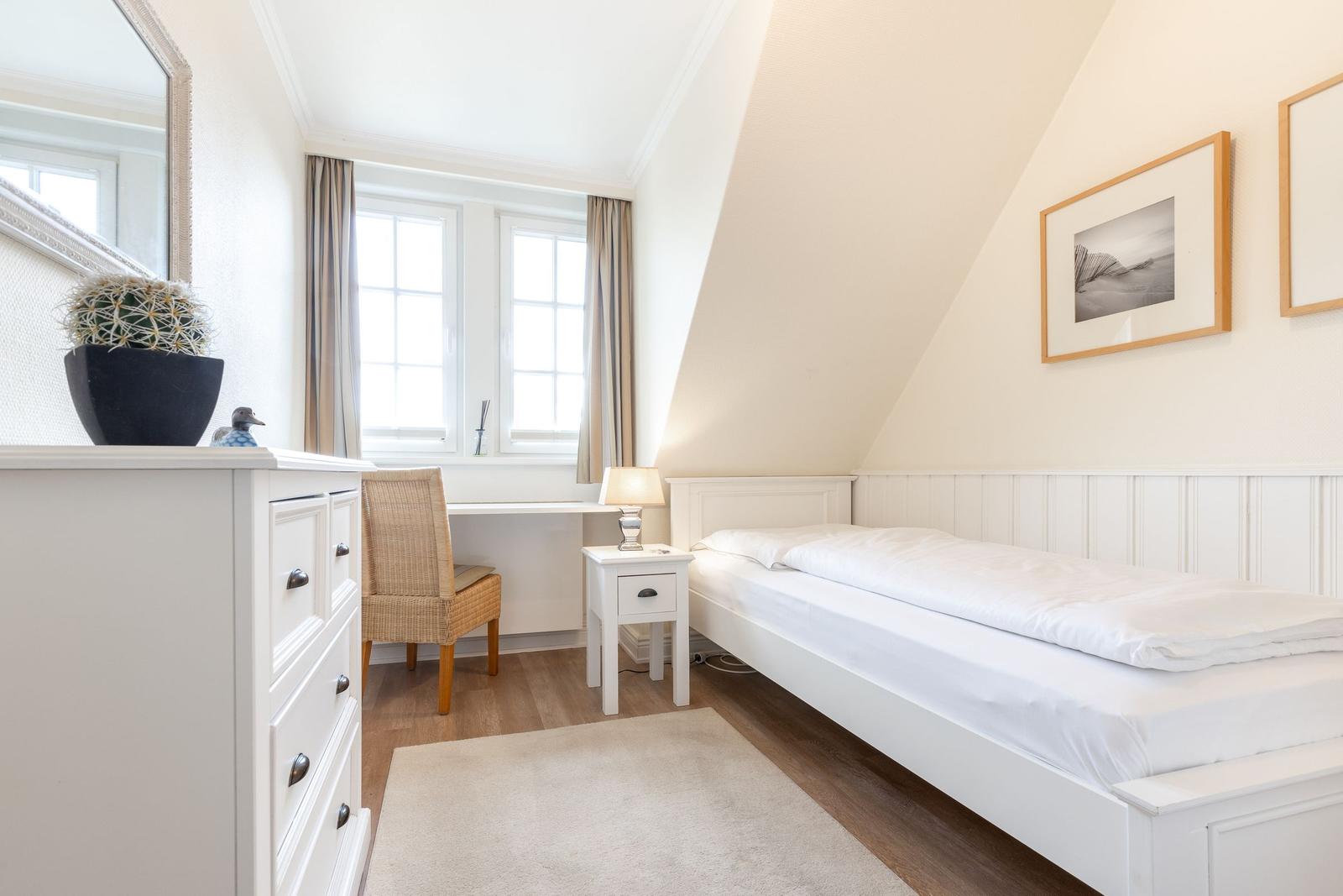 Schlafzimmer mit Doppelbett, Schreibtisch und Fenster