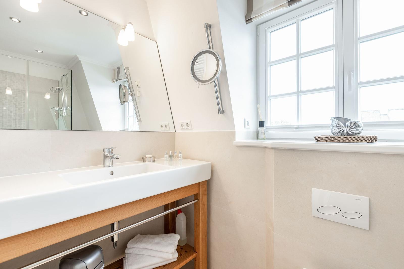 Badezimmer mit Waschbecken, Spiegel und Fenster