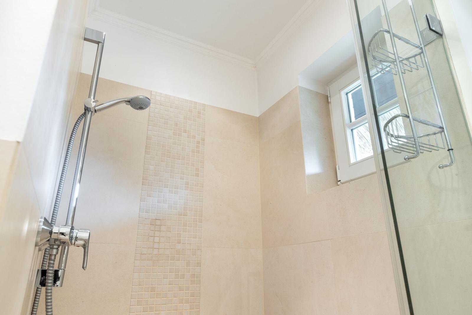 Dusche mit Glaswand, Duschbrause und Fenster