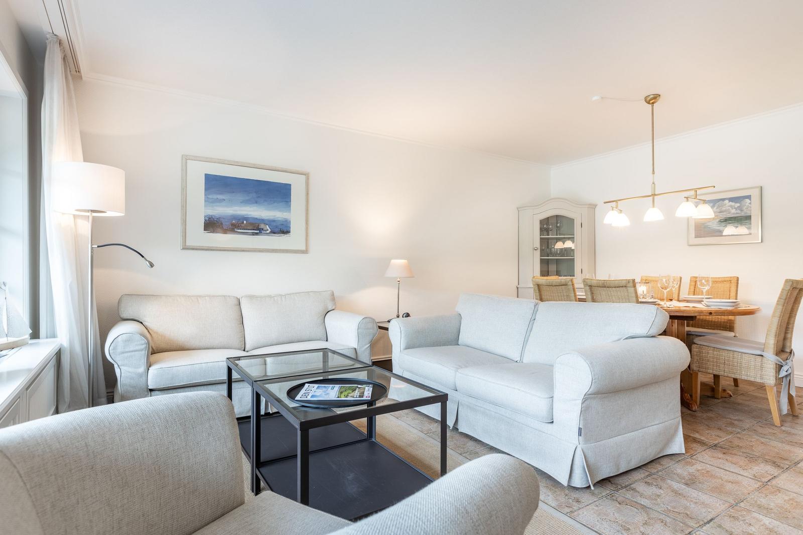 Wohn- und Essbereich mit zwei Sofas, Tisch und Stühlen.