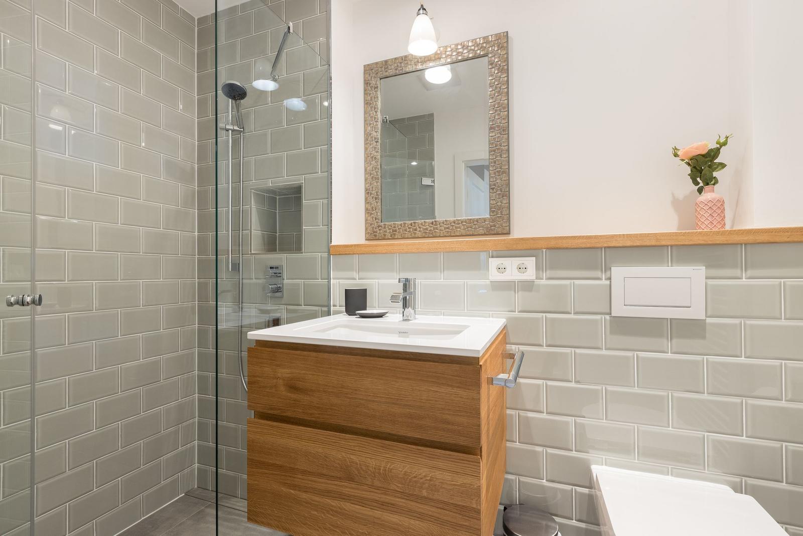 Badezimmer mit Dusche, Waschbecken und Spiegel.