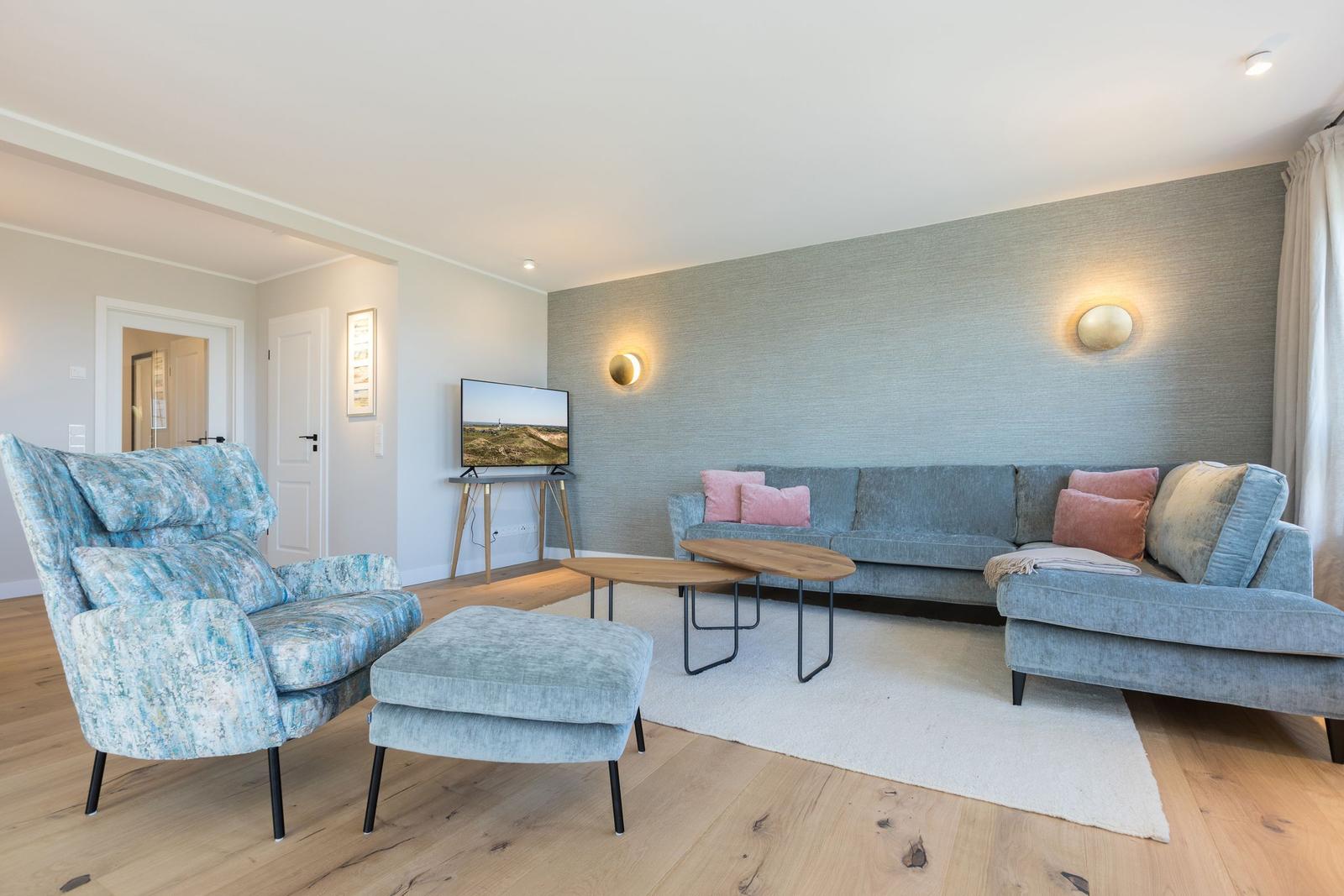 Wohnzimmer mit Sofa, Sessel und Fernseher
