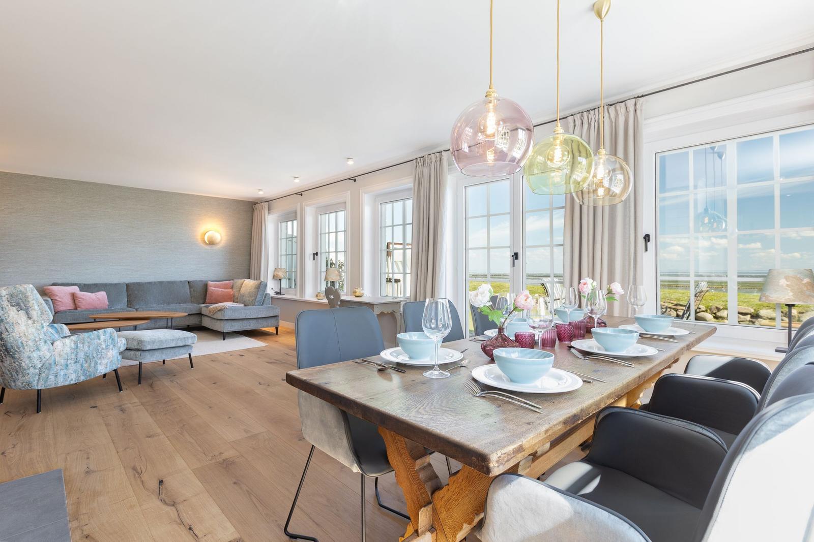 Esszimmer mit Holztisch und Sitzgelegenheiten. Wohnbereich mit Sofa und Fenstern.