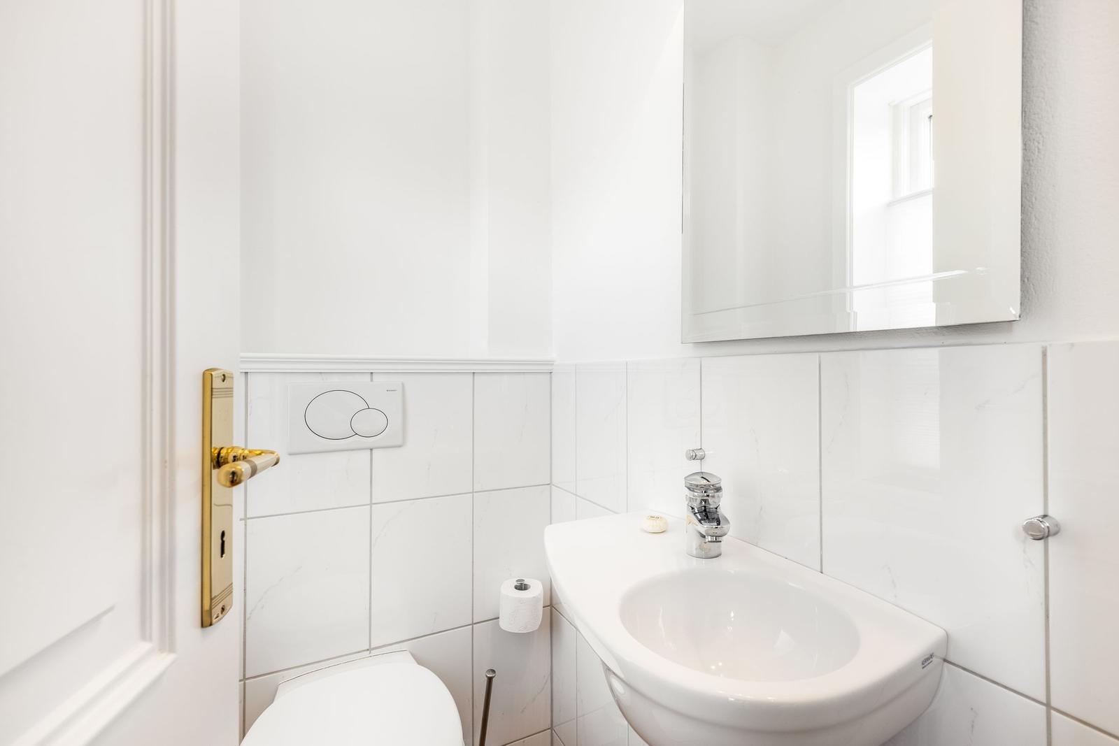 Badezimmer mit Toilette, Waschbecken und Spiegel.