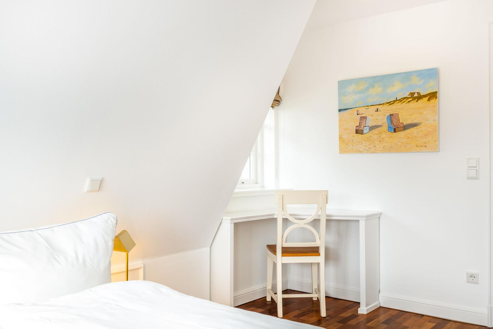 Schlafzimmer mit Schreibtisch, Bett und Wandbild