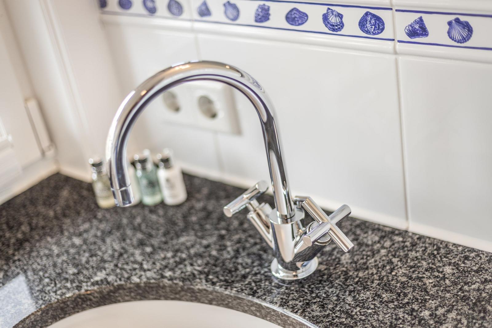 Waschbecken mit Chromarmatur und Marmor-Arbeitsplatte