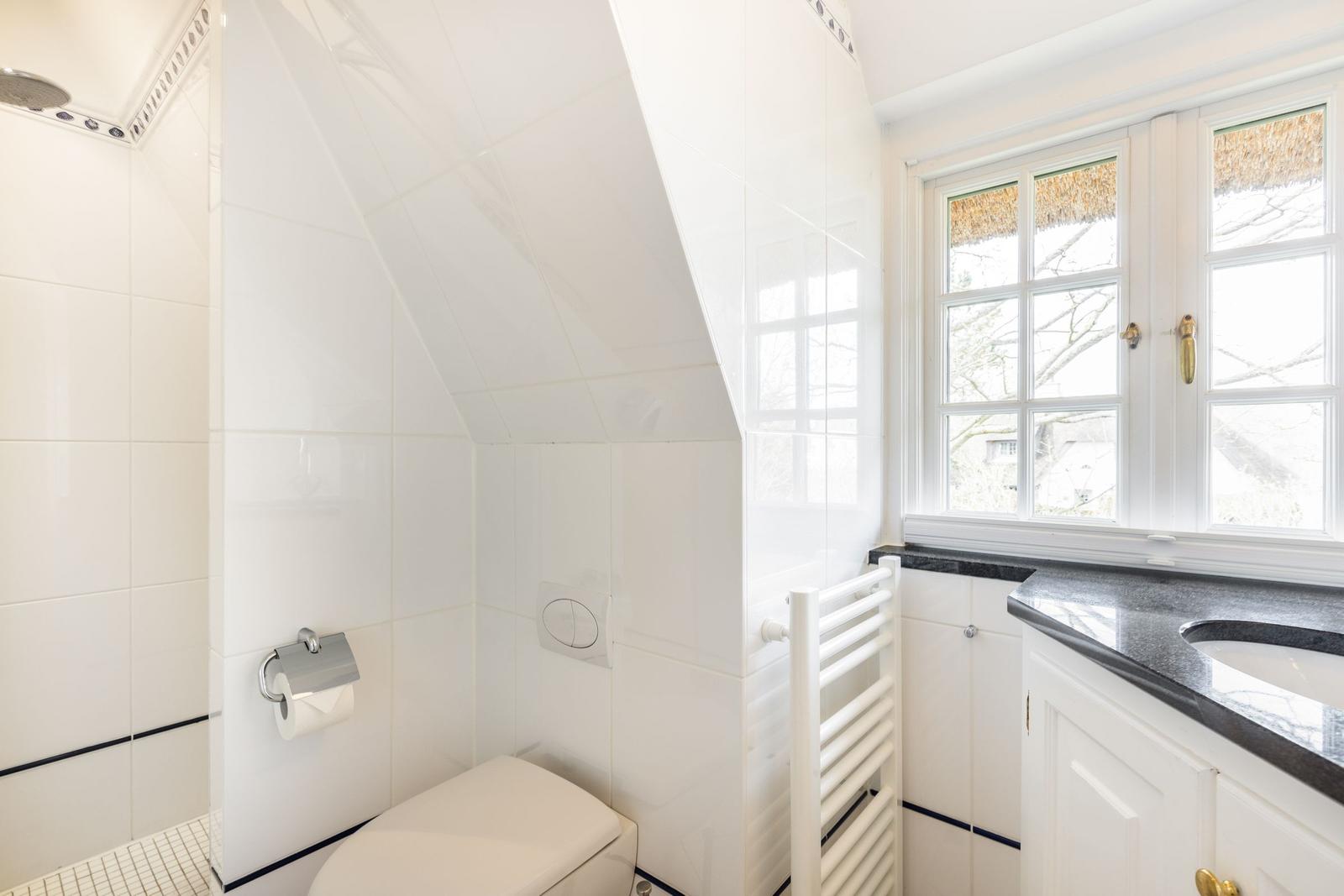 Badezimmer mit Dusche, Toilette und Waschbecken unter einem Dach