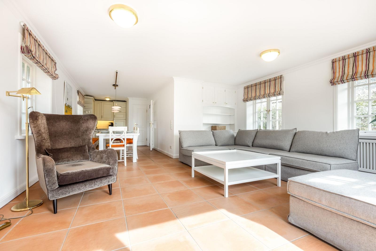 Wohn- und Essbereich mit Sofa, Sessel und Terrakottboden