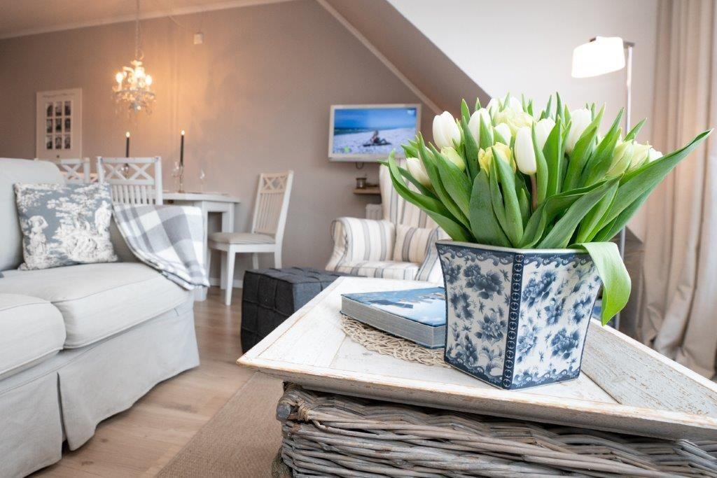 Wohnzimmer mit Sofa, Esstisch und Blumen in Blumentopf.