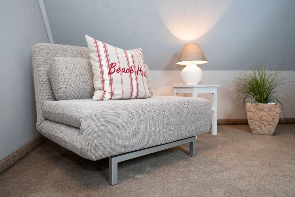 Sofa mit Kissen, Lampe und Pflanze in einem Raum mit Steigung.